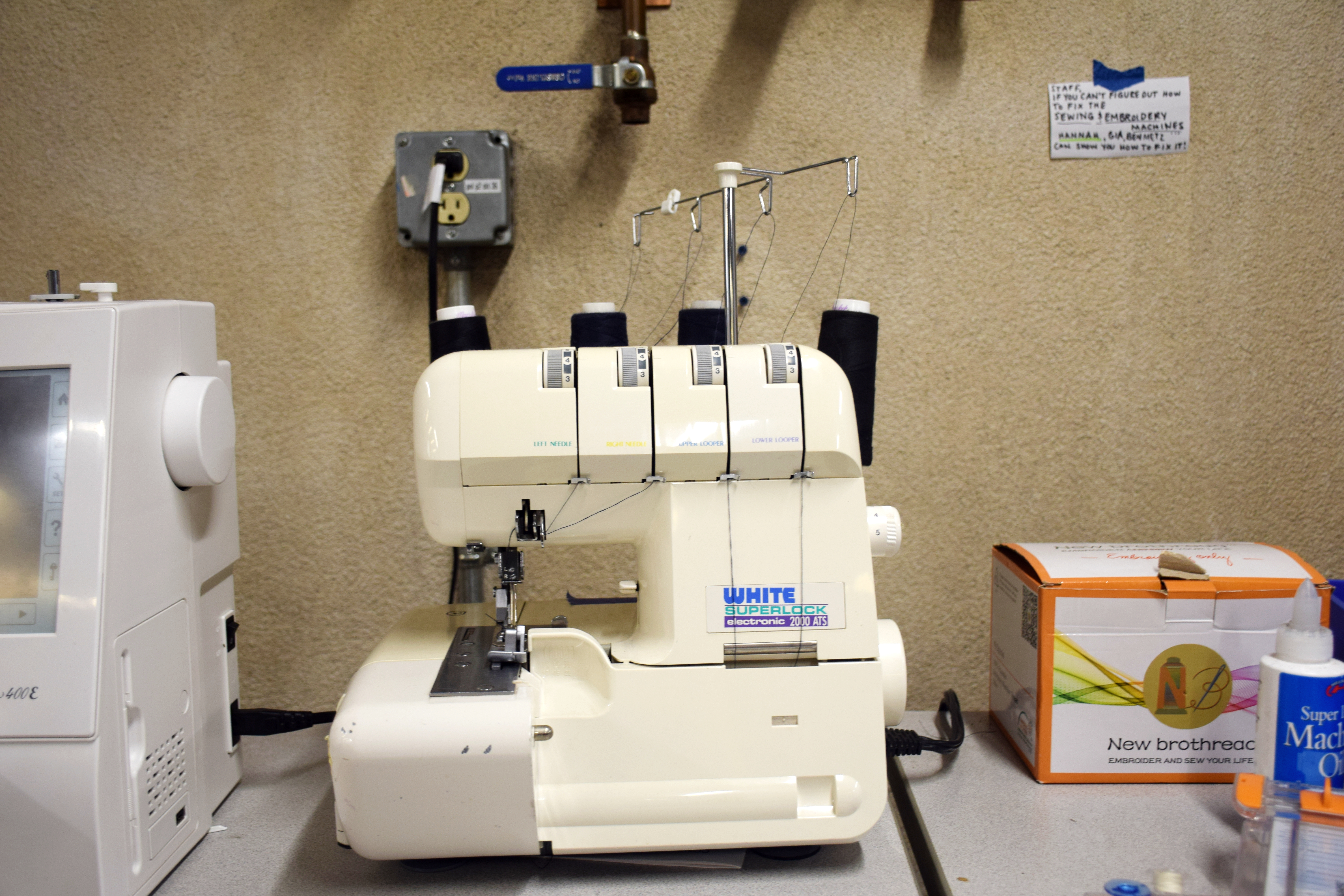 White Serger Machine with 4 Spools of Black Thread on Table