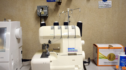 White Serger Machine with 4 Spools of Black Thread on Table